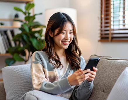 自宅のリビングでスマホを操作する女性の写真