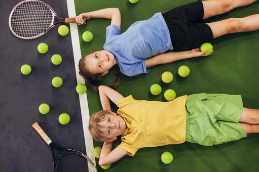 テニスボールに囲まれて寝転ぶ子供たち 男女,子供,外国人の写真素材