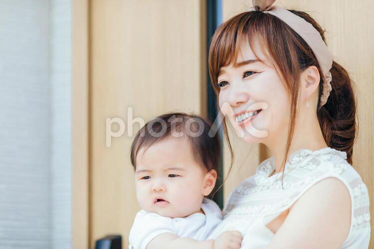 マイホームの前で赤ちゃんを抱く若い女性 親子,家族,赤ちゃんの写真素材