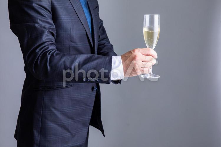 シャンパングラスを持ったスーツの男性  携帯電話,モバイル,インターネットの写真素材