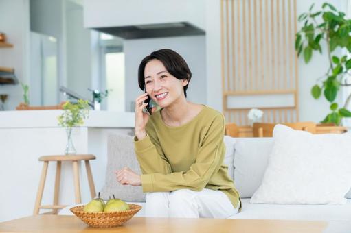 リビングで電話するミドルの女性 リビングで電話するミドルの女性の写真