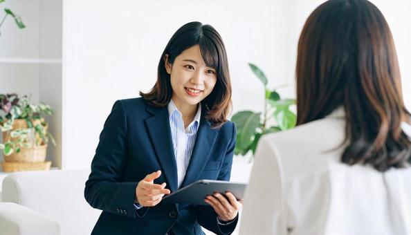 タブレットを使って説明する女性営業マン タブレットを使って説明する女性営業マンの写真