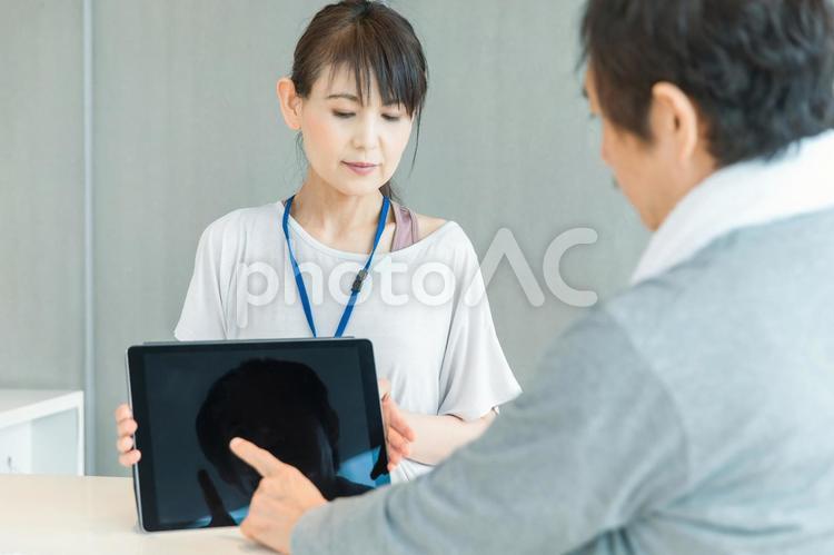 スポーツジムの受付をする女性（タブレットPC） スポーツジム,体験入会,受付の写真素材
