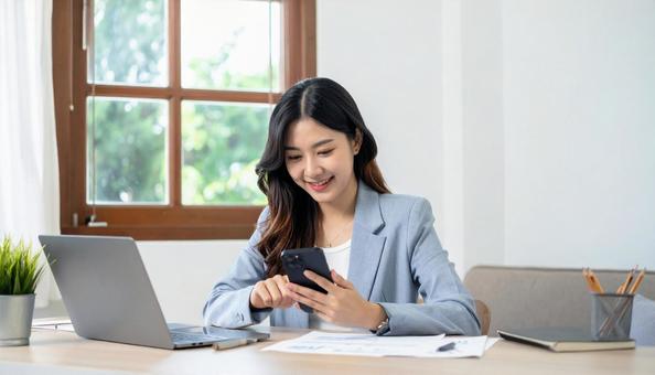 携帯を操作する女性の手元とノートパソコン 携帯を操作する女性の手元とノートパソコンの写真
