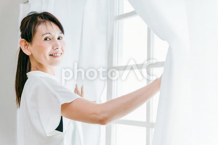 窓を開けるミドル世代の女性（普段着） 起床,朝活,寝起きの写真素材