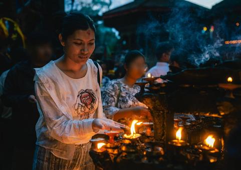 ネパールの寺院前で祈る女性とロウソクの火 ネパールの寺院前で祈る女性とロウソクの火の写真