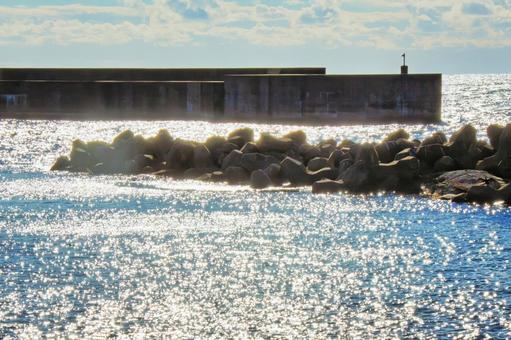 海面の反射光が眩しい静かな漁港の波止場 漁港,波止場,防波堤の写真素材
