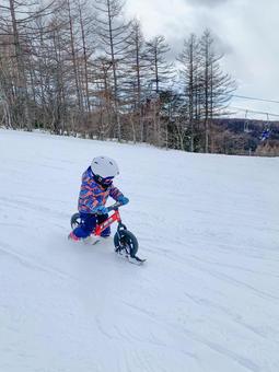 バランスバイクに乗ってゲレンデで遊ぶ子供 雪,スキー場,冬の写真素材