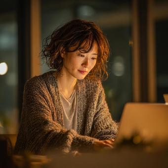 温かい光の中で仕事をする日本人女性 温かい光の中で仕事をする日本人女性の写真