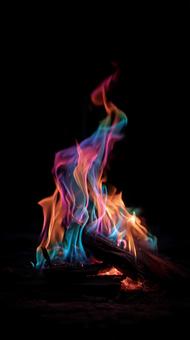 黒背景に燃え上がる多色の炎の写真
