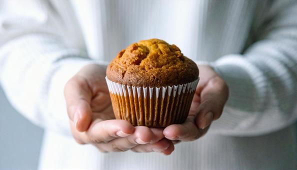 手に持ったスイートポテトのマフィン 手に持ったスイートポテトのマフィンの写真