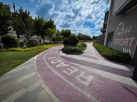 青空の下に続くピンク色の曲線遊歩道の写真