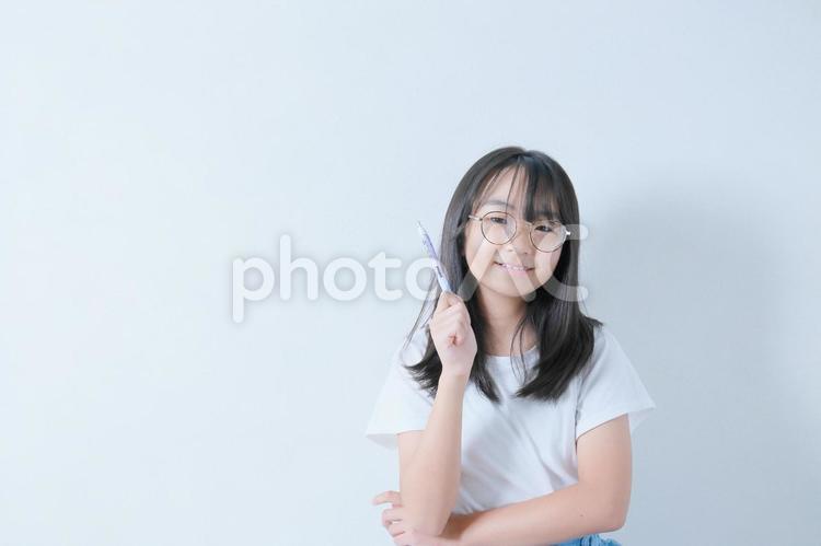 ボールペンを持つ眼鏡をかけた笑顔の少女 女性,日本人,若いの写真素材