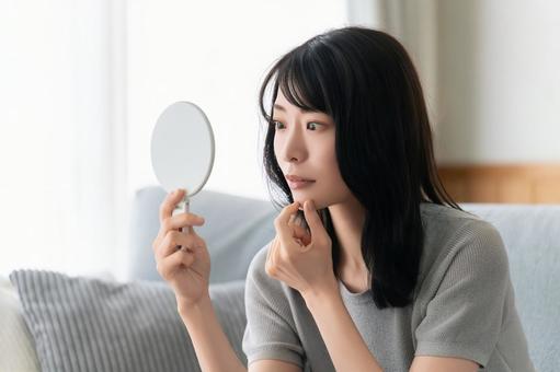 鏡で肌をチェックする女性 鏡で肌をチェックする女性 女性,美容,健康の写真素材