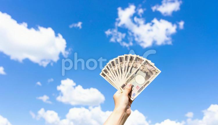 一万円を持つ手　青空背景 青空,お金,マネーの写真素材