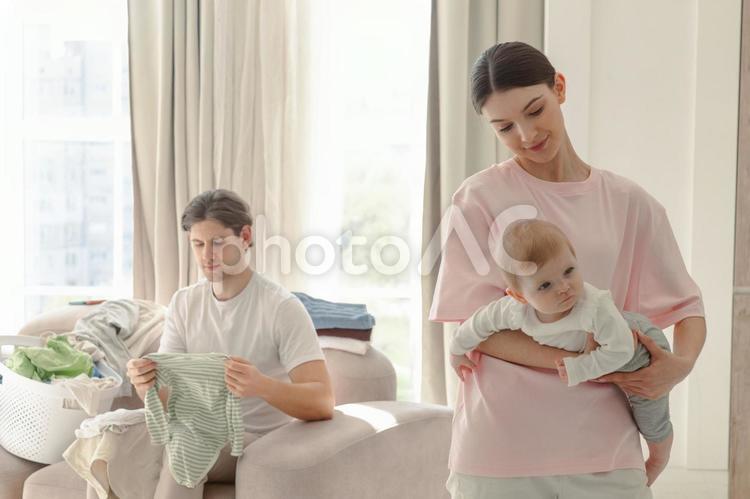 ソファーに座る男性と赤ちゃんを抱っこする女性 家族,赤ちゃん,女性の写真素材