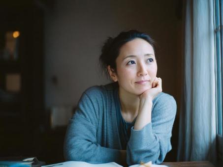 窓辺で考え事をする女性 窓辺で考え事をする女性の写真