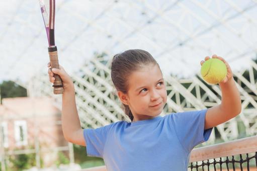 テニスボールを掲げる青いシャツの女の子 女の子,子供,外国人の写真素材
