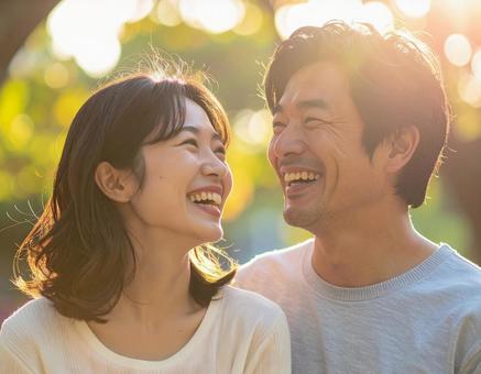 公園でお互いを見ながら笑う日本人男女 公園でお互いを見ながら笑う日本人男女の写真