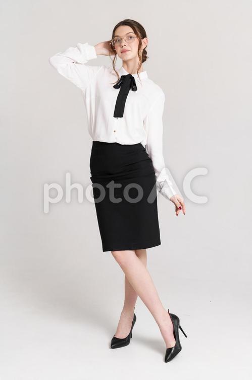カメラ目線で足をクロスしポーズするメガネの女性 女性,立つ,ポーズの写真素材