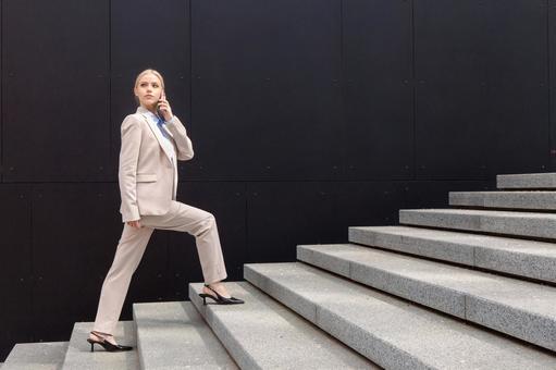 オフィスビルの外の階段を電話しながら登るビジネスウーマン ビジネスウーマン,ビジネス,女性の写真素材