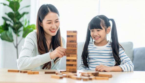 リビングで積み木遊びをする女の子と母親 リビングで積み木遊びをする女の子と母親の写真