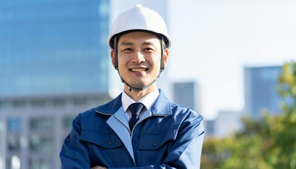 高層ビル前で腕組みする作業服の男性 高層ビル前で腕組みする作業服の男性の写真