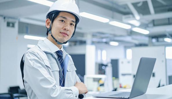 事務所で働く作業服の新入社員ビジネスマン 事務所で働く作業服の新入社員ビジネスマンの写真