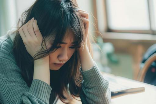 机で悩む若い女性の写真