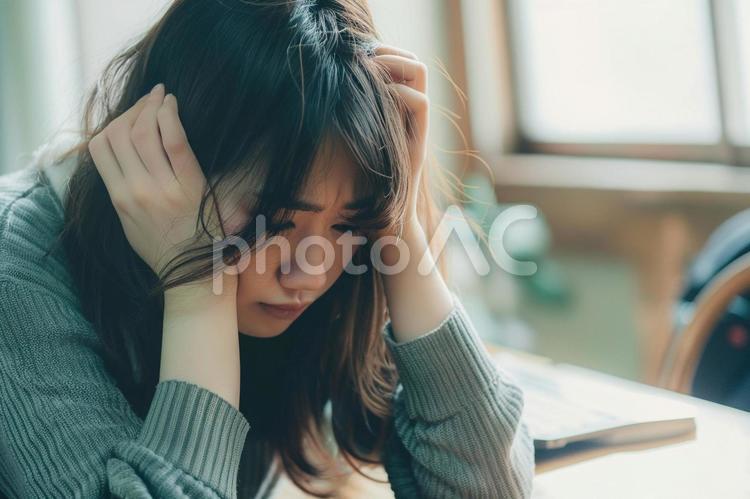 机で悩む若い女性 日本人女性,悩む,考え込むの写真素材