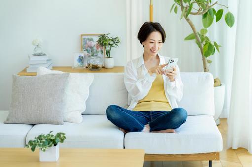 部屋でスマホを使うミドル女性 部屋でスマホを使うミドル女性 スマホ,笑顔,女性の写真素材