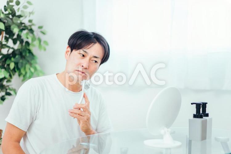 美顔ローラーを使う男性（困る） 美顔ローラー,顔痩せ,むくみの写真素材