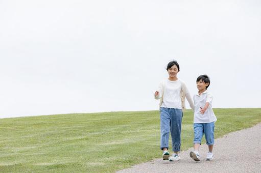 丘の上を笑顔で歩く子ども 丘の上を笑顔で歩く子どもの写真