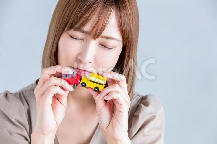 車のフィギアを持って微笑む女性 事故,車,自動車の写真素材