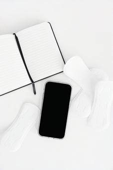 生理用ナプキンと黒画面のスマートフォンとノート 生理,月経,生理用品の写真素材