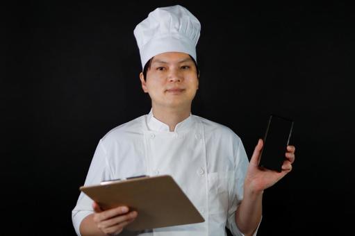スマホとメモを持つ料理人 スマホとメモを持つ料理人の写真