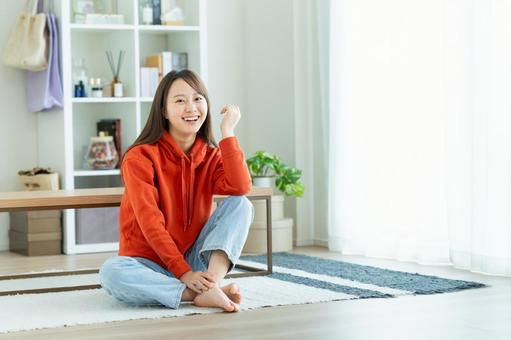 リビングでくつろぐ若い女性 リビングでくつろぐ若い女性 女性,笑顔,家の写真素材