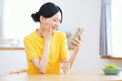 頬に手を当てスマホを見ている女性 女性,スマートフォン,持つの写真素材