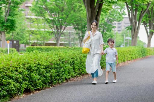 手を繋いで屋外を散歩する親子 手を繋いで屋外を散歩する親子の写真
