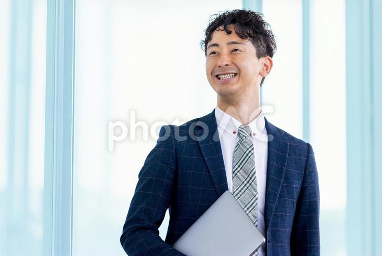 ノートパソコンを持つ笑顔のビジネスマン 男性,ビジネス,ビジネスマンの写真素材