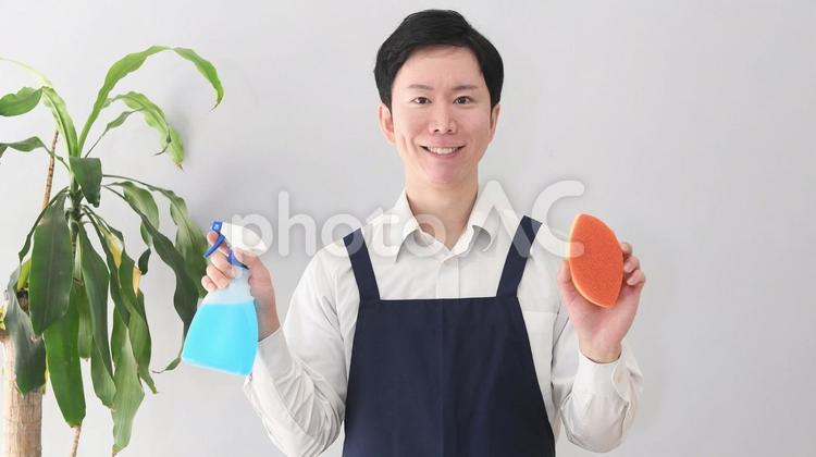 掃除グッズを持つ笑顔のエプロン姿の男性 エプロン,男性,清掃の写真素材