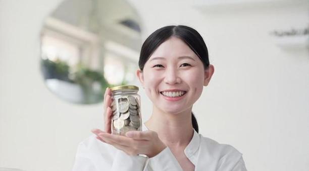 笑顔でお金が入った瓶を持つアジア人女性 貯金,500円玉,貯めるの写真素材