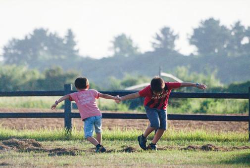 <素材>夏の夕暮れの公園で元気に遊ぶ兄弟 <素材>夏の夕暮れの公園で元気に遊ぶ兄弟の写真