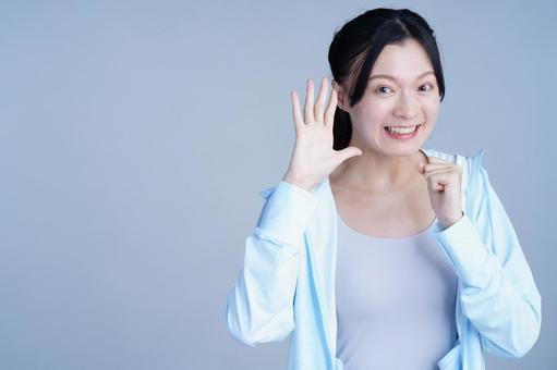 水色の服の女性が手を振る 女性,手を振る,手を広げるの写真素材