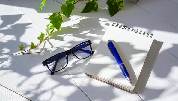 白木テーブルの上の新しいノートとペンの写真