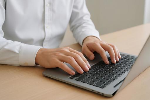 ノートPCにタイピング入力する男性の手元 ノートPCにタイピング入力する男性の手元の写真