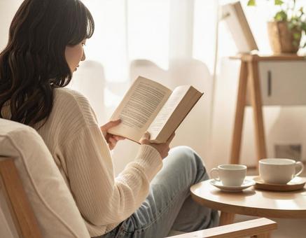 ソファーでくつろぎながら読書する女性 ソファーでくつろぎながら読書する女性の写真