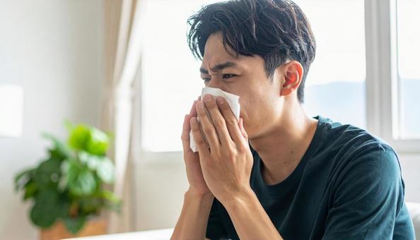 ティッシュで鼻をかむ日本人の若い男性 ティッシュで鼻をかむ日本人の若い男性の写真