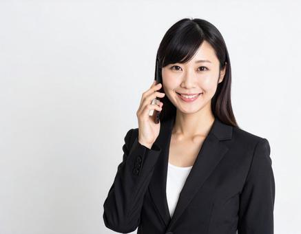 携帯電話で電話をする女性会社員の写真