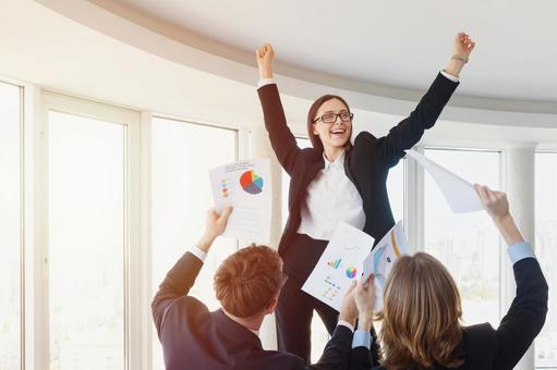 両手をあげ喜ぶメガネの女性の写真